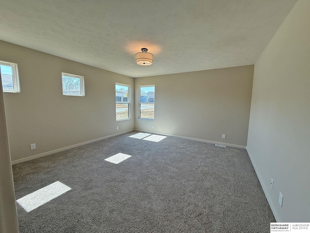 spare room with a healthy amount of sunlight, baseboards, and carpet