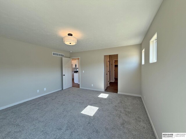 carpeted spare room with visible vents, a textured ceiling, and baseboards