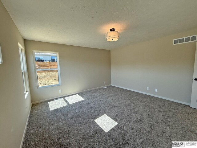 empty room with visible vents, baseboards, carpet, and a textured ceiling