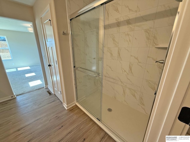 full bath with visible vents, wood finished floors, baseboards, and a stall shower