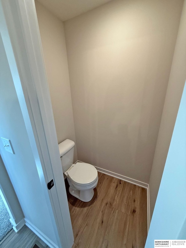 bathroom featuring baseboards, toilet, and wood finished floors