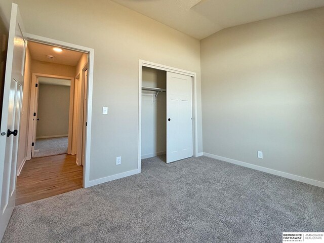 unfurnished bedroom featuring vaulted ceiling, carpet, baseboards, and a closet