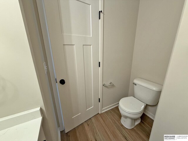 bathroom featuring toilet, baseboards, and wood finished floors