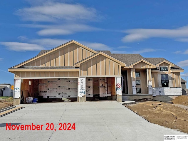 view of front of home with driveway, board and batten siding, an attached garage, and a shingled roof