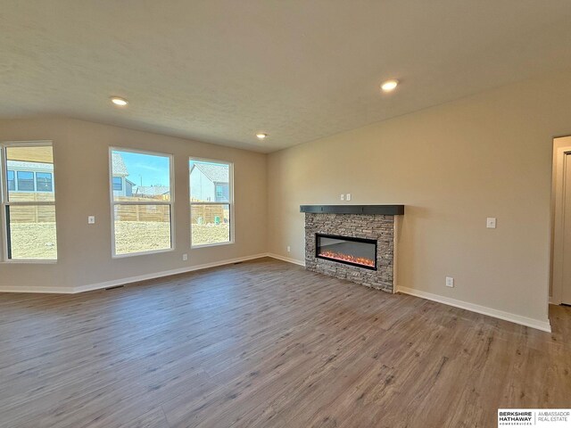 unfurnished living room featuring a healthy amount of sunlight, wood finished floors, and a fireplace