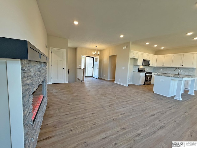 kitchen featuring stainless steel appliances, light wood-style floors, white cabinetry, tasteful backsplash, and open floor plan