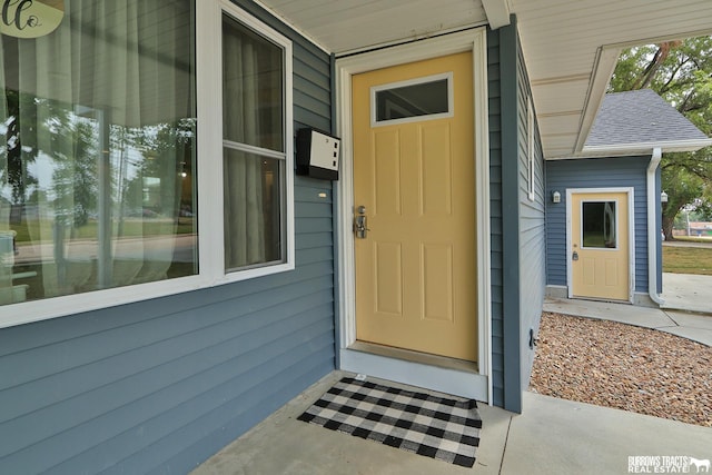 doorway to property featuring roof with shingles