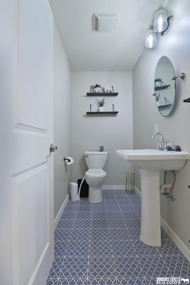 bathroom with toilet, visible vents, and baseboards