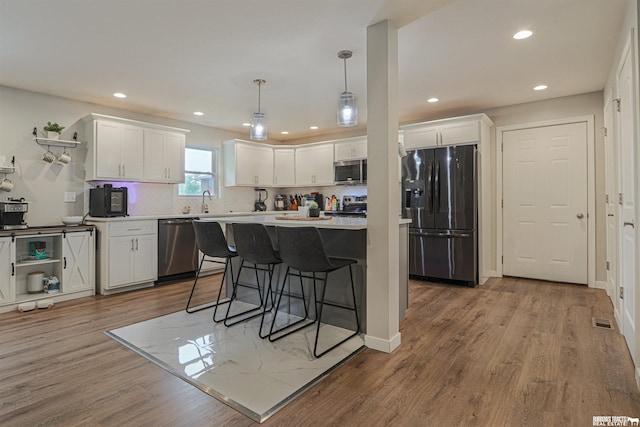 kitchen with open shelves, light countertops, hanging light fixtures, appliances with stainless steel finishes, and white cabinetry