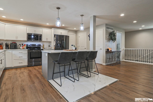 kitchen with white cabinetry, appliances with stainless steel finishes, light countertops, and a center island