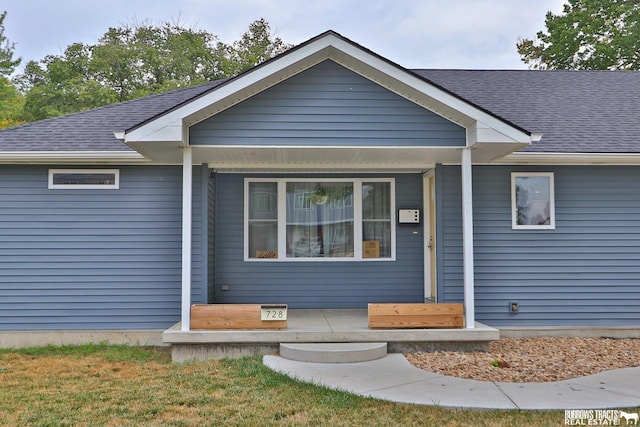 view of front of home featuring a front lawn and roof with shingles