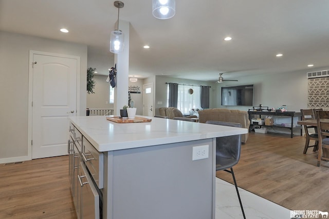 kitchen featuring a kitchen island, open floor plan, decorative light fixtures, light countertops, and recessed lighting