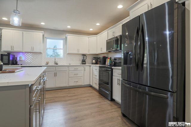 kitchen featuring appliances with stainless steel finishes, light stone countertops, white cabinets, and pendant lighting