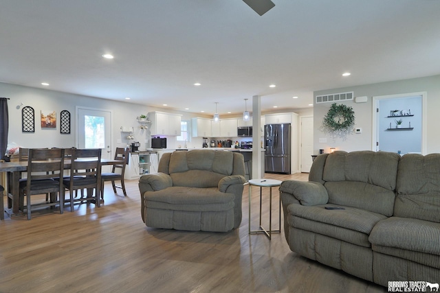 living area with visible vents, wood finished floors, and recessed lighting