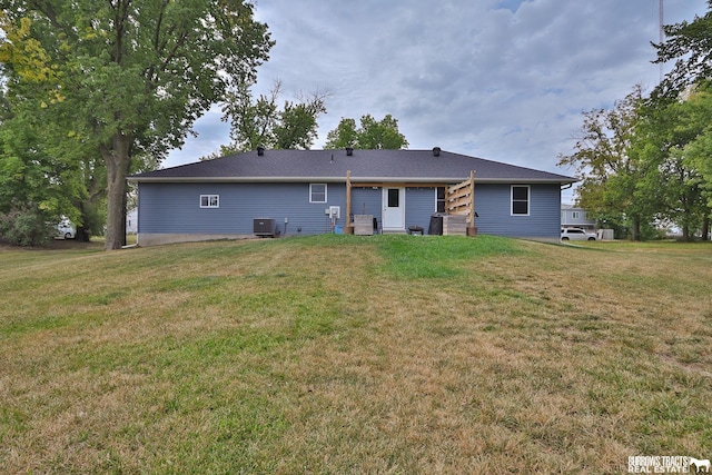 back of house featuring central air condition unit and a yard