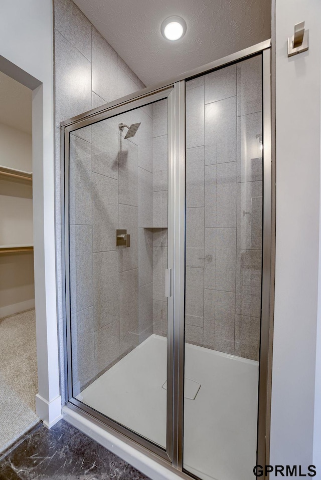 bathroom with a textured ceiling and a shower with shower door