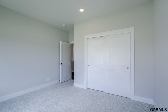 unfurnished bedroom featuring a closet and light colored carpet