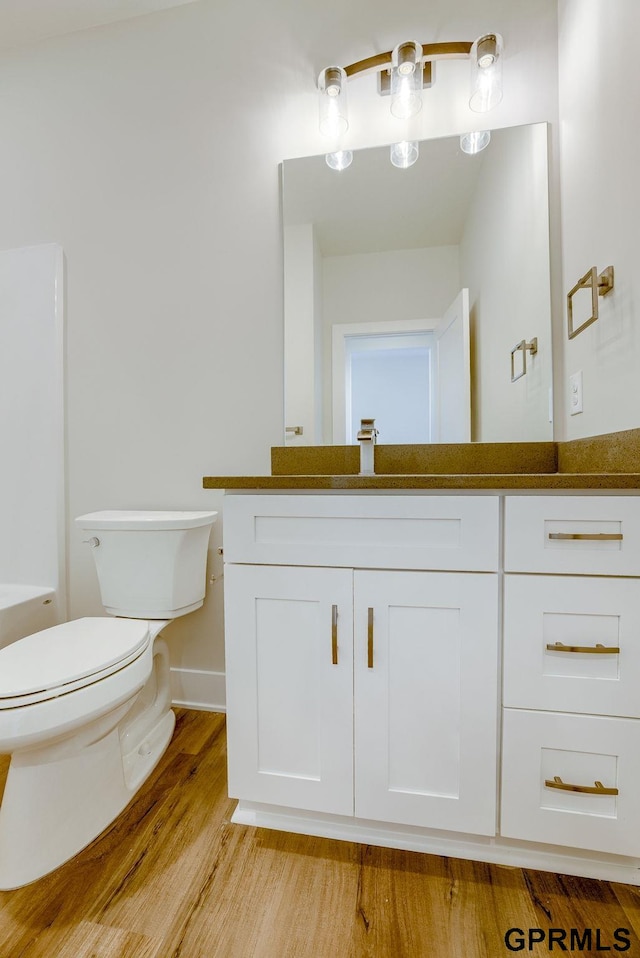 bathroom with hardwood / wood-style floors, toilet, and vanity