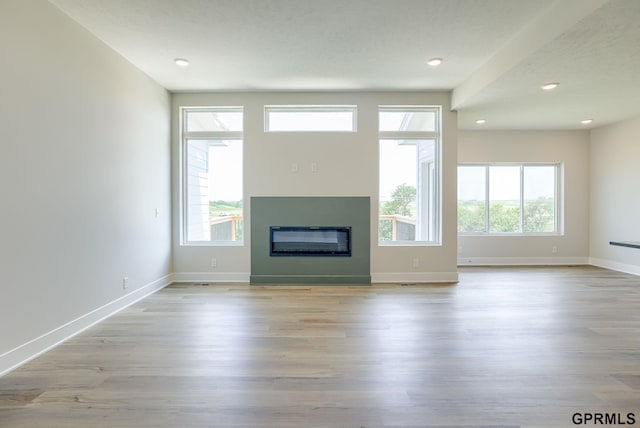 unfurnished living room with light hardwood / wood-style floors and a healthy amount of sunlight