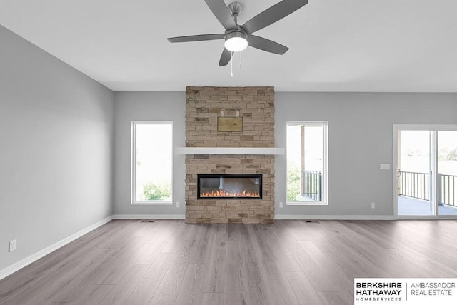 10210 S 110th Ave, Papillion, NE 68046 - unfurnished living room featuring wood finished floors, healthy amount of natural light, a ceiling fan, and a fireplace