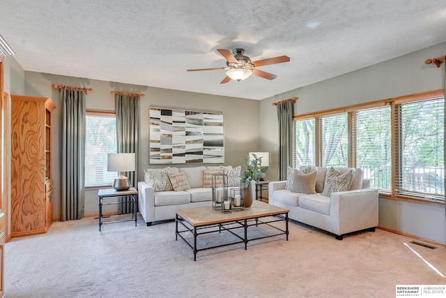 living room with a textured ceiling, a healthy amount of sunlight, ceiling fan, and light colored carpet