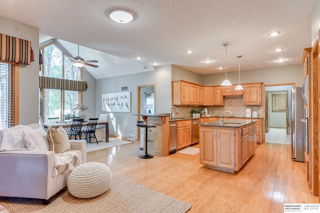 kitchen with backsplash, appliances with stainless steel finishes, light hardwood / wood-style floors, ceiling fan, and pendant lighting