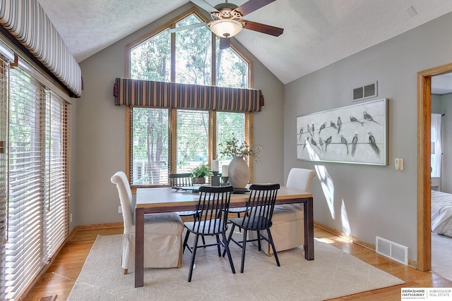 dining room featuring a textured ceiling, ceiling fan, high vaulted ceiling, and light hardwood / wood-style floors