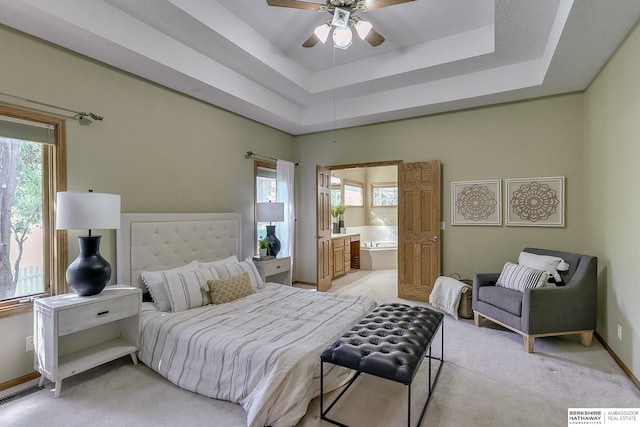 carpeted bedroom featuring ensuite bath, a raised ceiling, and ceiling fan