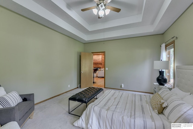 bedroom featuring a tray ceiling, light colored carpet, and ceiling fan