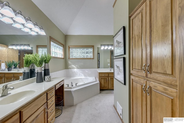 bathroom with tiled bath, vaulted ceiling, and vanity