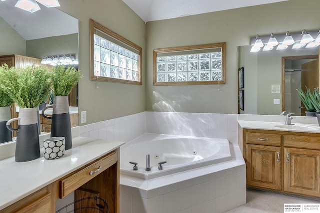 bathroom featuring vanity, vaulted ceiling, and a relaxing tiled tub