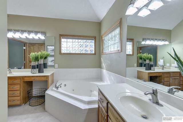 bathroom featuring a textured ceiling, tiled bath, vaulted ceiling, and vanity