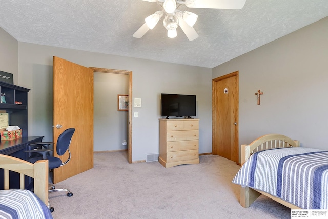 bedroom featuring ceiling fan, light carpet, and a textured ceiling