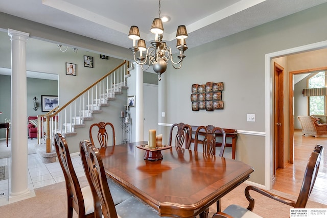 dining area featuring light wood-type flooring, decorative columns, and a chandelier