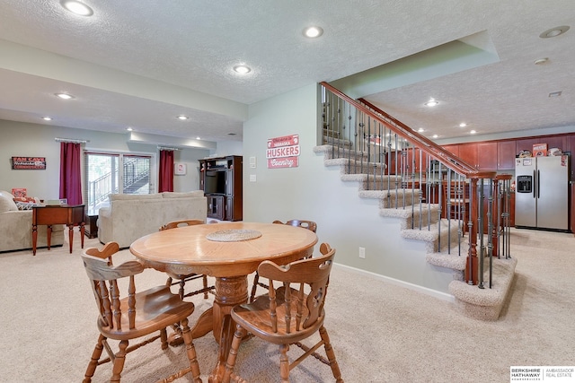 dining area with a textured ceiling and light carpet