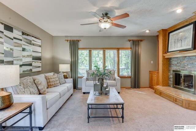 carpeted living room with a textured ceiling, ceiling fan, and a fireplace