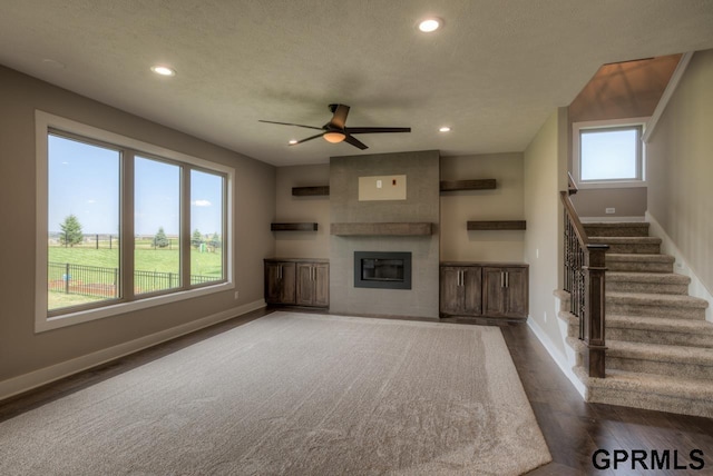 unfurnished living room with a textured ceiling, a large fireplace, ceiling fan, and hardwood / wood-style flooring