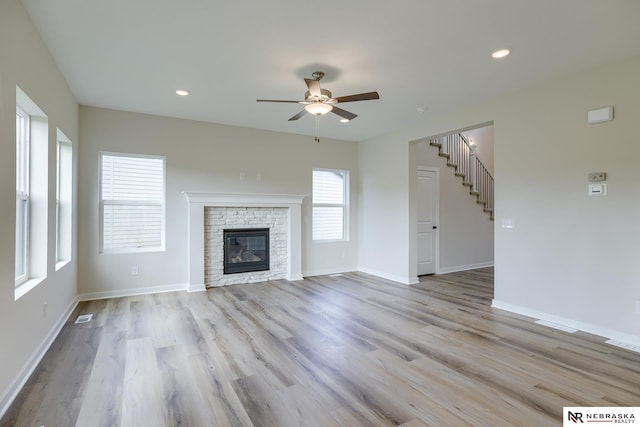 unfurnished living room with ceiling fan, a fireplace, light wood-type flooring, and baseboards