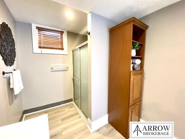 bathroom with a stall shower, baseboards, and wood finished floors