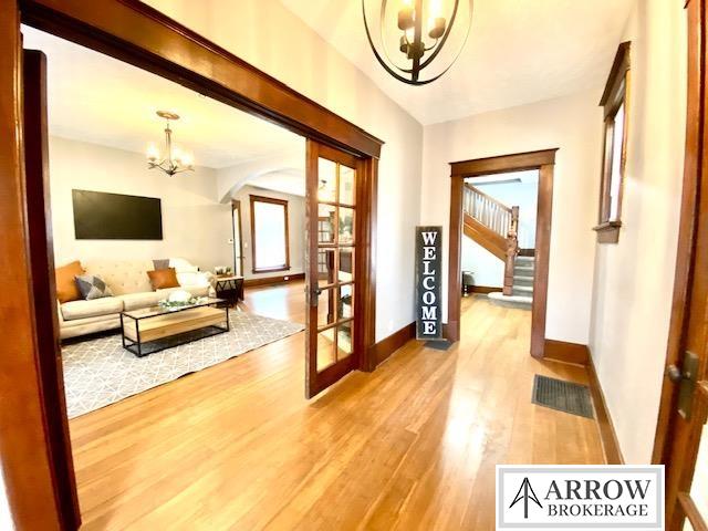 hall featuring french doors, hardwood / wood-style flooring, and an inviting chandelier