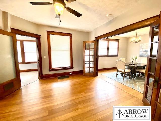 dining space with ceiling fan with notable chandelier, light wood-type flooring, visible vents, and baseboards