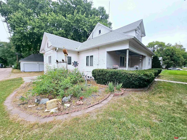 view of front of house featuring an outbuilding, a front yard, a garage, and a porch