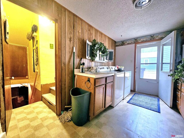 kitchen featuring a textured ceiling, wood walls, and separate washer and dryer