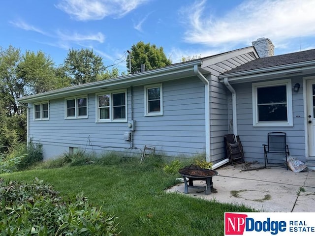 back of property with a fire pit and a lawn