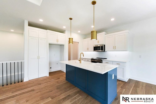 kitchen featuring recessed lighting, stainless steel appliances, wood finished floors, white cabinetry, and pendant lighting