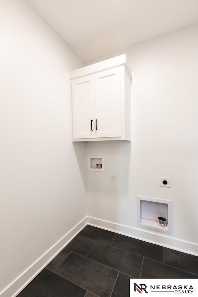 laundry area with hookup for an electric dryer, dark tile patterned flooring, washer hookup, baseboards, and cabinet space