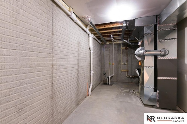 unfinished basement featuring heating unit and brick wall