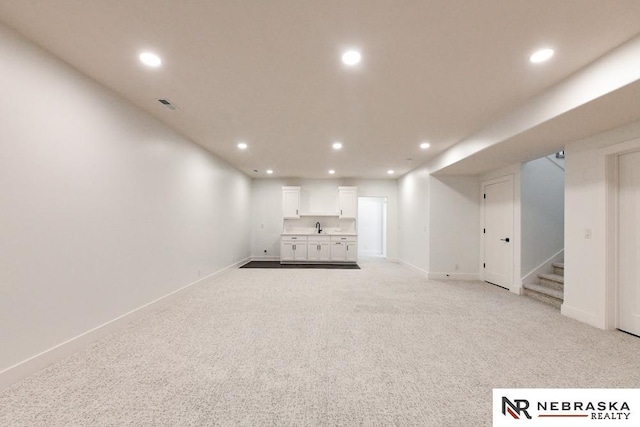 unfurnished living room with recessed lighting, light carpet, stairway, and baseboards