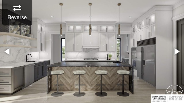 kitchen with under cabinet range hood, a kitchen breakfast bar, stainless steel built in fridge, and a sink