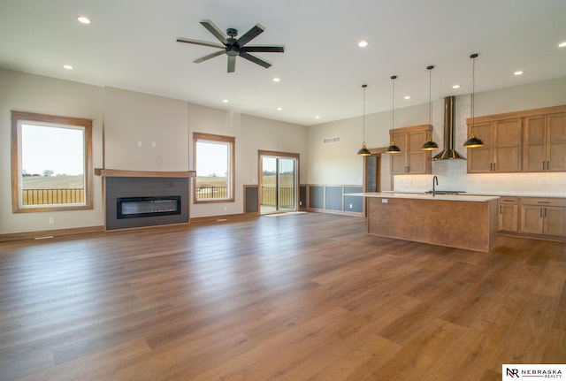 325 S Lakeview Way, Ashland, NE 68003 - kitchen with wall chimney exhaust hood, open floor plan, wood finished floors, a kitchen island with sink, and light countertops